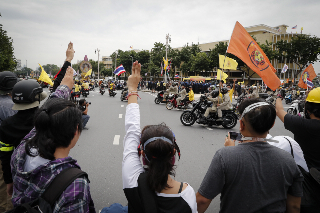군부 제정 헌법 개정과 왕실 개혁 등을 요구하는 태국 반정부 시위대가 민중봉기 47주년 기념일인 지난 14일(현지시간) 방콕 민주주의 기념비 인근에서 독재에 저항하는 의미인 ‘세 손가락 경례’를 하고 있다. 세 손가락 경례는 2012년 영화 ‘헝거게임:판엠의 불꽃’에 등장하는 민중 저항 제스처에서 유래한 것으로 알려졌다./AP연합뉴스
