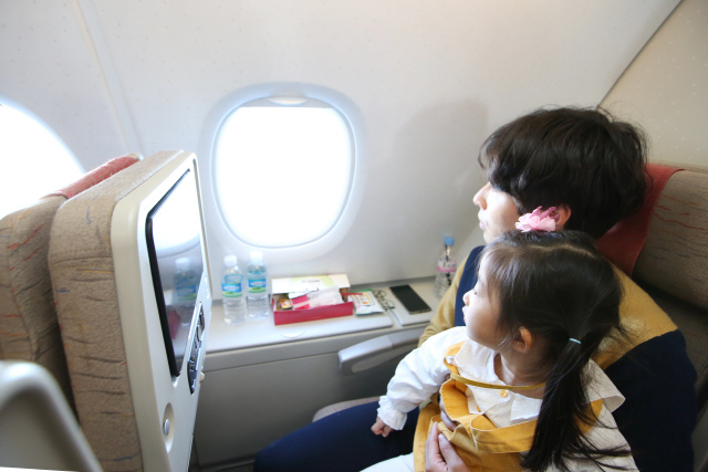 아시아나항공의 A380 한반도 일주 비행 관광상품을 이용한 탑승객이 창문으로 지상 풍경을 내려다보고 있다./사진제공=아시아나항공