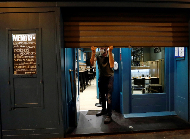 지난 21일(현지시간) 밤 스페인 북부 나바라 팜플로나 시내의 한 술집에서 종업원이 영업을 끝내고 문을 닫고 있다. 코로나19 확산세가 다시 거세지자 이 지역 보건당국은 이날부터 최소 14일 간 밤 10시 이후 식당과 술집의 영업을 금지한다고 밝혔다./EPA연합뉴스