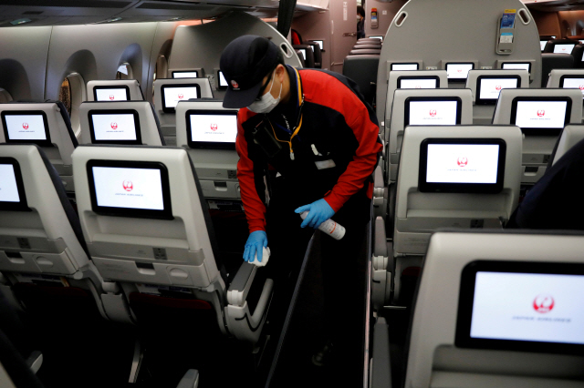 일본항공(JAL) 직원이 마스크와 장갑을 착용한 채 기내에서 코로나19 방역 작업을 하고 있다. /로이터연합뉴스