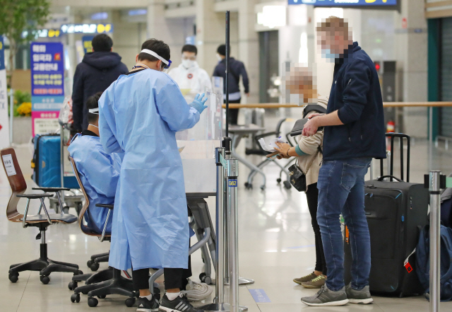 22일 인천국제공항을 통해 입국한 승객들이 관계자에게 여권을 제시하고 있다. /연합뉴스