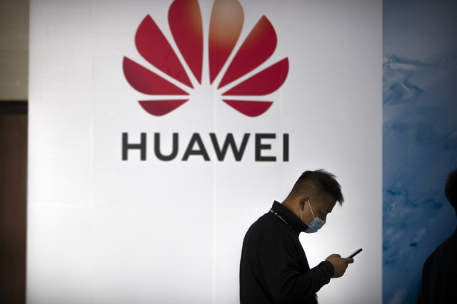 베이징의 한 남성이 화웨이 광고판 앞에서 스마트폰을 보고 있다. /AP=연합뉴스