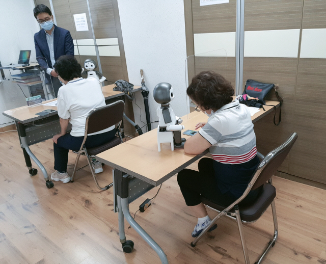 서울 강남구에 거주하는 어르신들이 인공지능 로봇의 도움을 받아 디지털기기 활용법을 배우고 있다./사진제공=강남구