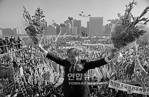 1987년 12월 노태우 민정당 대통령 후보가 서울 여의도 유세장에서 환호하는 수많은 인파들을 향해 두손을 들어 답례하고 있다. /연합뉴스