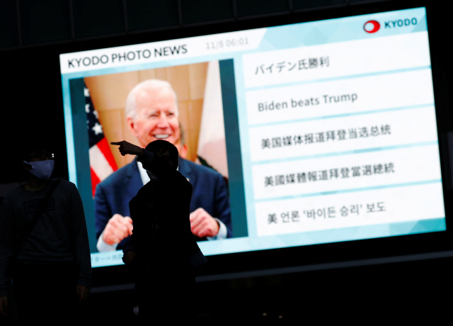 8일 일본 도쿄에서 바이든 후보의 미 대선 승리를 전하는 대형 전광판 뉴스 앞을 시민들이 지나고 있다. /로이터연합뉴스