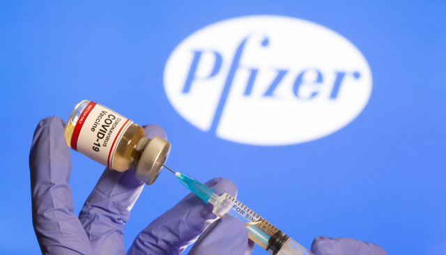 FILE PHOTO: FILE PHOTO: A woman holds a small bottle labeled with a “Coronavirus COVID-19 Vaccine” sticker and a medical syringe in front of displayed Pfizer logo in this illustration taken, October 30, 2020. REUTERS/Dado Ruvic/File Photo/File Photo/File Photo        <저작권자(c) 연합뉴스, 무단 전재-재배포 금지>