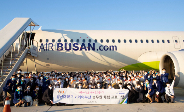 지난 10일 열린 ‘에어부산 캐빈크루 스탠바이’에 참여한 와이즈유(영산대학교) 항공관광학과 학생들이 항공기(BX8910편) 앞에서 기념촬영을 하고 있다./사진제공=와이즈유