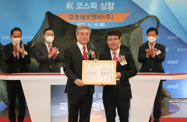 교촌에프앤비㈜ 코스피 상장 기념식이 열린 12일 서울 여의도 한국거래소에서 소진세(왼쪽) 교촌에프앤비 회장과 임재준 한국거래소 유가증권시장 본부장이 상장계약서를 들고 기념촬영을 하고 있다./사진제공=교촌에프앤비