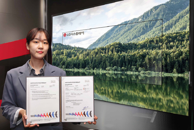 LG디스플레이 직원이 OLED TV 앞에서 SGS 친환경제품 인증서를 선보이고 있다./사진제공=LG디스플레이