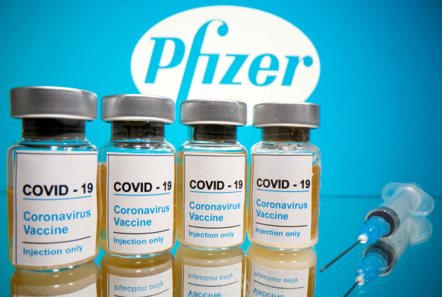 FILE PHOTO: Vials with a sticker reading, “COVID-19 / Coronavirus vaccine / Injection only” and a medical syringe are seen in front of a displayed Pfizer logo in this illustration taken October 31, 2020. REUTERS/Dado Ruvic/Illustration/File Photo        <저작권자(c) 연합뉴스, 무단 전재-재배포 금지>
