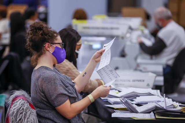 미국 대선 경합주인 조지아주 애틀랜타의 스테이트팜 아레나에 마련된 풀턴 카운티 선거관리소에서 개표 요원들이 부재자투표 용지를 확인하고 있다. /EPA연합뉴스