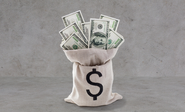 business, finance, investment, saving and currency concept - close up of dollar paper money in bag on bank table over gray concrete background