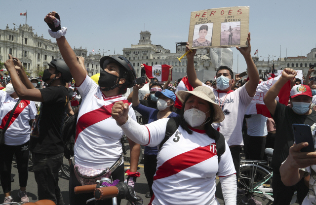 15일(현지시간) 페루의 마누엘 메리노 임시 대통령이 사임하겠다고 발표하자 수도 리마의 산마르틴 광장에 모인 반(反)정부 시위대가 전날 경찰의 과잉진압으로 사망한 시민 2명의 사진을 들고 시위 구호를 외치고 있다. /AP연합뉴스