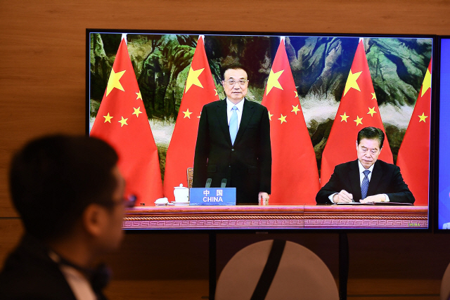 15일(현지시간) 중국의 리커창(가운데) 총리가 역내포괄적경제동반자협정(RCEP) 서명에 참여하는 모습이 TV를 통해 보여지고 있다./AFP연합뉴스
