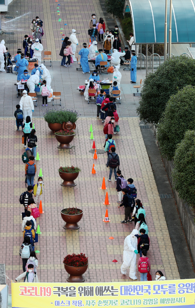 16일 오전 광주 북구의 한 초등학교에 마련된 이동식 선별진료소에서 학생들이 코로나19 전수 검사를 받고 있다./연합뉴스