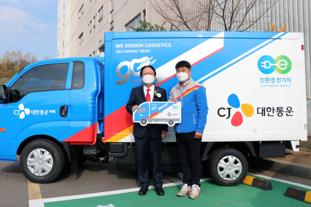 박근희(왼쪽) CJ대한통운 대표이사 부회장이 택배기사에게 전기화물차를 인도하는 차량전달식을 가지며 기념사진 촬영을 하고 있다./사진제공=CJ대한통운