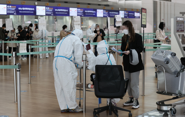 11일 오후 인천국제공항 1터미널 출국장 중국 선전행 항공기 체크인카운터에서 승객들이 신종 코로나바이러스 감염증(코로나19)에 걸리지 않았다는 것을 증명하는 음성확인서를 두 장을 준비하고 있다. /연합뉴스