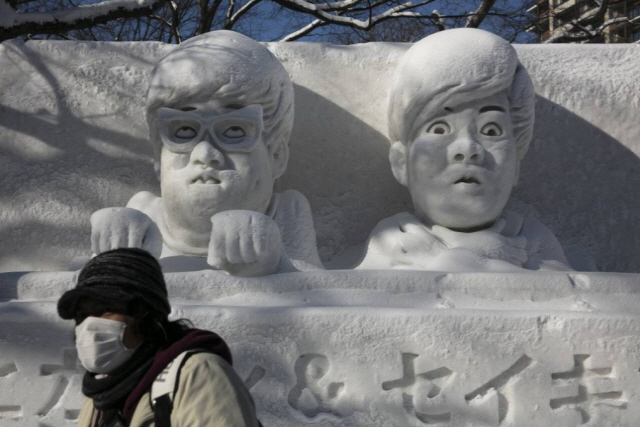올해 2월 제71회 삿포로 눈축제가 열리고 있는 일본 홋카이도 삿포로의 오도리 공원에서 마스크를 쓴 관광객이 눈 조각상 앞을 지나가고 있다. /AP연합뉴스