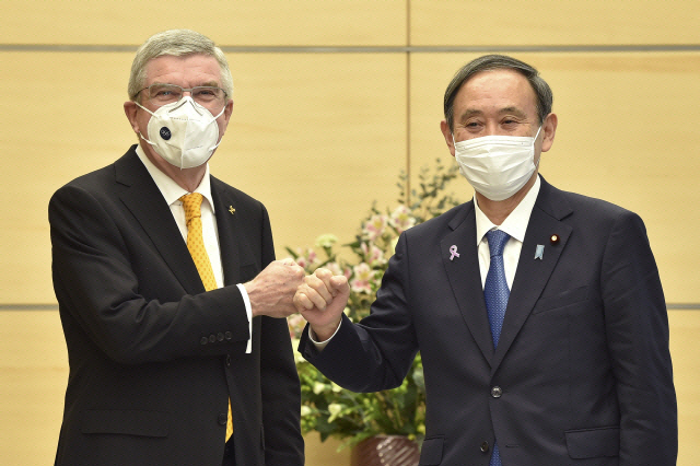 토마스 바흐(왼쪽) 국제올림픽위원회(IOC) 위원장과 스가 요시히데 일본 총리가 16일 도쿄 총리 관저에서 만나 주먹 악수를 하고 있다./AP연합뉴스