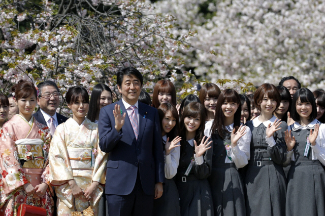 아베 신조(앞줄 왼쪽 세번째) 전 일본 총리가 재임 기간인 지난 2015년 4월18일 도쿄 신주쿠 교엔 국립공원에서 열린 ‘벚꽃을 보는 모임’ 행사에서 시민들과 기념촬영을 하고 있다. 23일 요미우리신문은 일본 검찰이 2018년 4월 열린 ‘벚꽃 행사’ 전야제에서 아베 전 총리 측이 참가자들의 행사비 일부를 지원했는지를 수사하고 있다고 보도했다. /블룸버그 자료사진