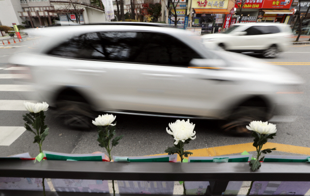 지난 23일 광주 북구 운암동의 한 어린이보호구역 횡단보도 옆 펜스에 걸려 있는 국화 등 하얀색 꽃과 손편지./연합뉴스