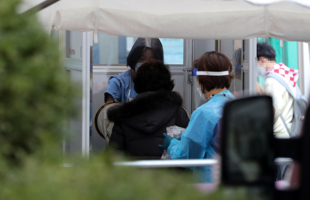 코로나19 선별진료소에 한 시민이 코로나19 검사를 받고 있다./연합뉴스