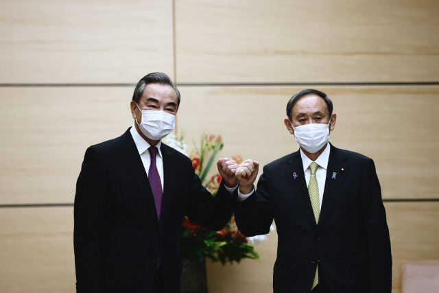 스가 요시히데(오른쪽) 일본 총리가 25일 도쿄 총리 관저에서 왕이 중국 외교부장과 악수 대신 팔꿈치 인사를 하고 있다. /EPA연합뉴스