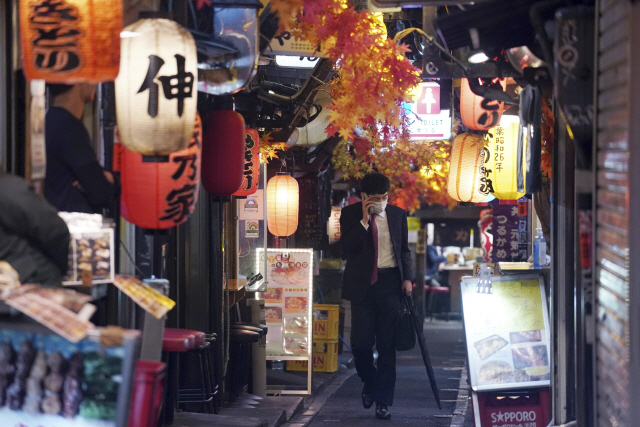 25일 일본 도쿄에서 마스크를 착용한 한 남성이 뒷골목 술집 거리를 따라 홀로 걸어가고 있다. 이날 일본 도쿄도에서는 나흘 만에 400명을 초과하는 코로나19 확진자가 새로 확인됐으며 27일에는 하루 신규 확진자가 570명에 달해 사상 최다 기록을 세웠다. /연합뉴스