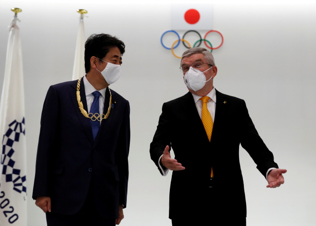 지난 16일 국제올림픽위원회(IOC)로부터 올림픽 훈장을 받은 아베 신조(왼쪽) 전 일본 총리와 토마스 바흐 IOC위원장./로이터연합뉴스