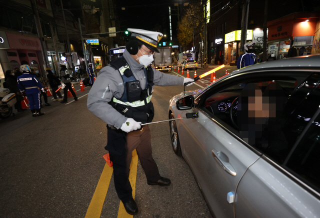 27일 저녁 서울 마포구 도로에서 경찰들이 ‘비접촉 음주 감지기’를 이용해 음주운전 단속을 하고 있다./연합뉴스