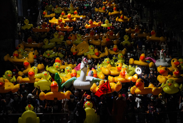 태국의 반정부 시위대가 29일(현지시간) 방콕에서 군주제 개혁을 요구하는 시위의 상징으로 떠오르고 있는 노란색 오리 고무보트를 들고 왕실 경비 11보병연대 본부를 향해 행진하고 있다./AP연합뉴스