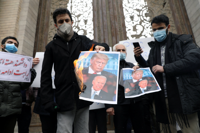 지난달 28일 이란 테헤란의 외교부 앞에서 핵과학자 모센 파크리자데에 대한 테러에 항의해 도널드 트럼프 미국 대통령과 조 바이든 당선인의 사진을 태우는 학생들./연합뉴스