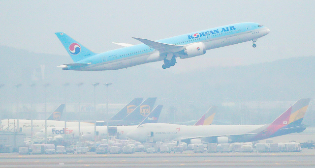 지난달 18일 오전 인천국제공항 주기장에 세워진 아시아나항공 여객기 위로 대한항공 여객기가 이륙하고 있다./연합뉴스