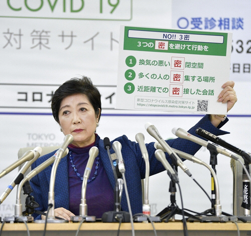 고이케 유리코(小池百合子) 일본 도쿄도지사가 올해 3월 25일 도쿄도청에서 열린 기자회견에서 ‘3밀’(密)을 피하는 행동을 하라는 메시지가 적인 패널을 들고 있다. /교도연합뉴스
