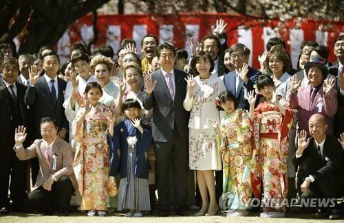2019년 4월 13일 아베 신조 당시 일본 총리가 부인 아키에 여사와 함께 도쿄의 공원인 ‘신주쿠 교엔’에서 열린 ‘벚꽃을 보는 모임’ 행사에서 참석자들과 기념사진을 찍고 있다. /교도연합뉴스