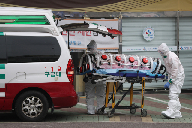 7일 오전 신종 코로나바이러스 감염증(코로나19) 확진자가 무더기로 발생한 울산시 남구 양지요양병원 앞에서 소방대원들이 확진자를 구급차로 옮기고 있다. /연합뉴스