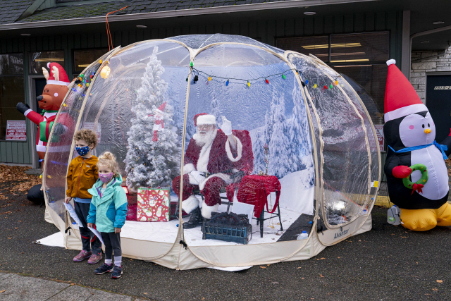 6일(현지 시간) 미국 워싱턴주 시애틀에서 어린이들이 사회적 거리 두기를 위해 스노볼 텐트 안에 있는 산타와 사진을 찍고 있다. /AFP연합뉴스
