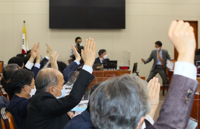 7일 밤 국회에서 열린 정무위원회 전체회의에서 진행된 ‘사회적 참사의 진상규명 및 안전사회 건설 등을 위한 특별법, 금융그룹 감독법, 공정거래법’ 등 안건 변경 상정에 대한 표결에서 더불어민주당 의원들은 손을 들어 찬성하는 반면 국민의힘 의원들 반대하고 있다./연합뉴스