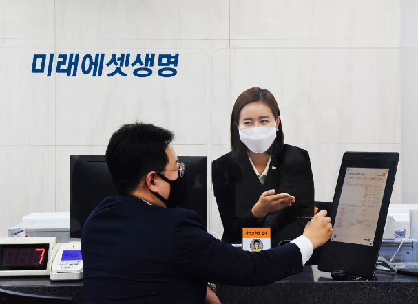 미래에셋생명 직원이 10일 서울의 한 지점에서 고객에게 페이퍼리스 시스템 구축 계획의 일환으로 도입한 전자문서 사용법을 안내하고 있다. /사진제공=미래에셋생명