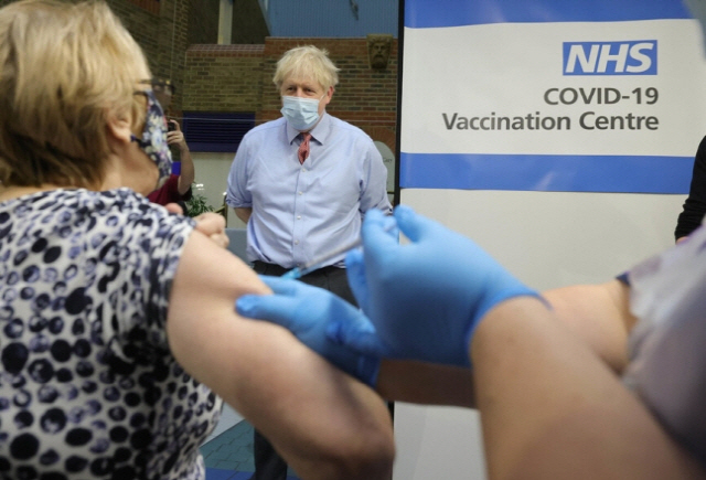 9일 영국 런던에서 보리스 존슨 총리가 한 시민이 화이자의 코로나19 백신을 맞는 모습을 보고 있다./신화= 연합뉴스