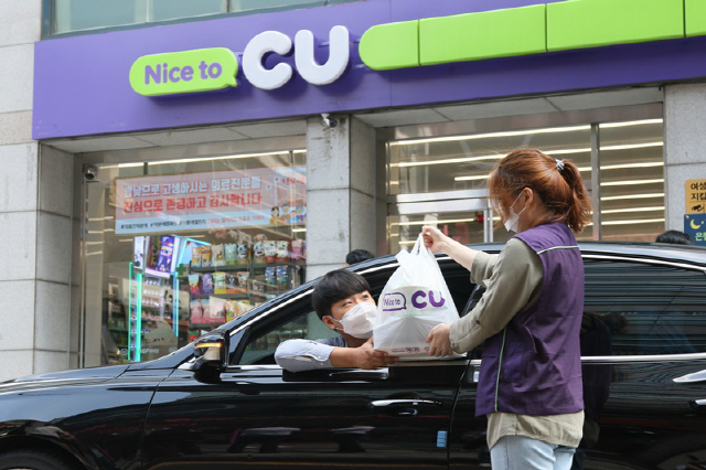 CU 점포 앞에서 고객이 미리 오윈 앱으로 주문·결제한 상품을 근무자가 고객의 차로 전달하고 있다./사진제공=BGF리테일