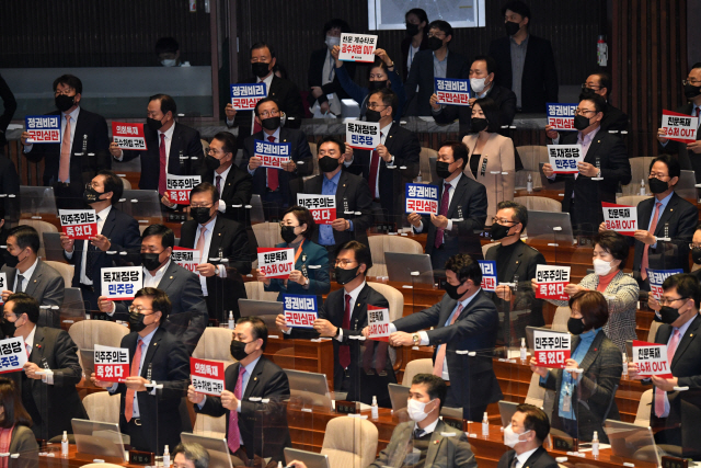 야당의 비토(거부)권을 무력화하는 내용을 담은 ‘고위공직자범죄수사처(공수처)법’ 개정안이 10일 국회 본회의에서 통과되자 국민의힘 의원들이 손 팻말을 들고 기립해 구호를 외치며 항의하고 있다. /연합뉴스