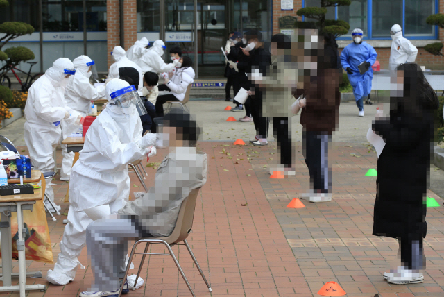 10일 오후 광주 광산구 한 고등학교에 설치된 선별진료소에서 학생들이 신종 코로나바이러스 감염증(코로나19) 검사를 받고 있다. 이 학교에서 한 교사가 가족의 김장 모임에 참석한 뒤 확진 판정을 받았다./연합뉴스