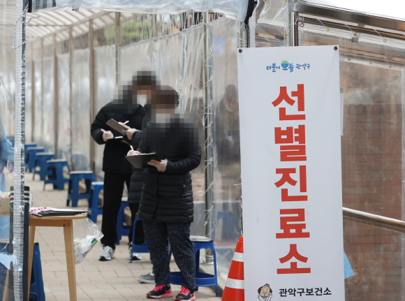 10일 서울 관악구보건소 선별진료소에서 시민들이 신종 코로나바이러스 감염증 검사를 받기 전 문진표를 작성하고 있다.       /연합뉴스