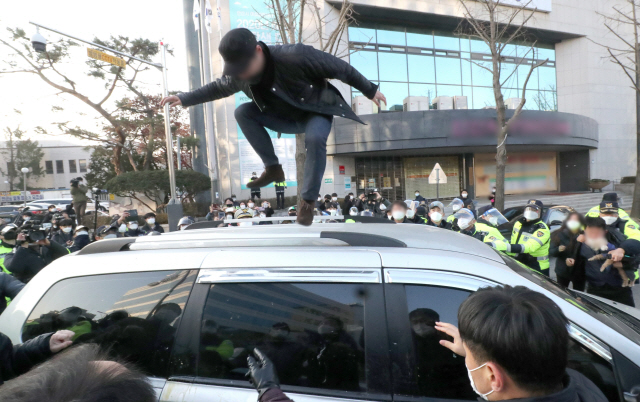 지난 12일 한 시민이 조두순이 탑승한 관용차량 위에 올라서서 뛰고 있다./연합뉴스