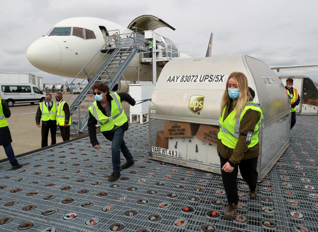 UPS 직원들이 13일(현지시간) 켄터키주 루이스빌의 공항에서 화이자 백신이 든 컨테이너를 옮기고 있다. /로이터연합뉴스