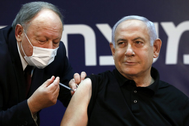 베냐민 네타냐후(오른쪽) 이스라엘 총리가 19일(현지 시간) 수도 텔아비브 시바메디컬센터에서 이스라엘 최초로 화이자·바이오엔테크의 코로나19 백신을 맞고 있다. 네타냐후 총리는 백신 접종을 격려하기 위해 가장 먼저 나섰으며 그의 접종 장면은 방송을 통해 생중계됐다. /UPI연합뉴스