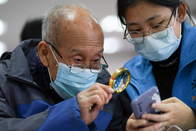 중국 베이징에서 한 노인이 자원봉사자의 도움으로 스마트폰 사용법을 익히고 있다. 중국에서 전 분야의 디지털화가 가속화되는 가운데 노인 소외 현상이 중대한 사회문제가 되고 있다. /신화연합뉴스