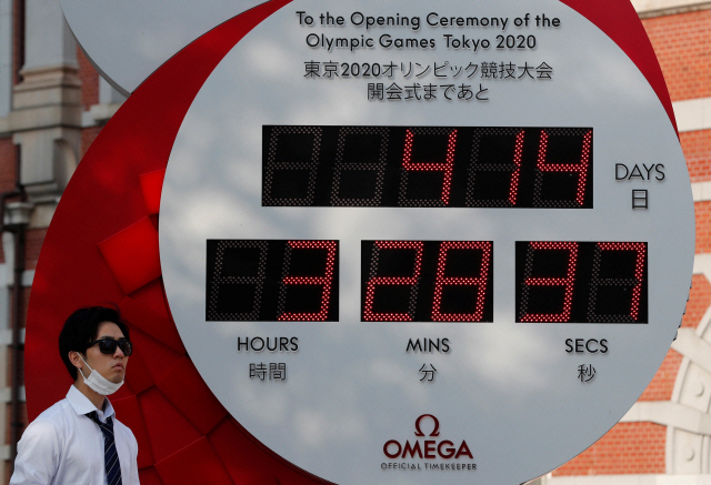 지난 6월 4일 일본 도쿄에 설치된 2020 도쿄올림픽 개막식을 기준으로 맞춰진 카운트시계 앞을 마스크를 착용한 한 남성이 지나가고 있다./로이터연합뉴스