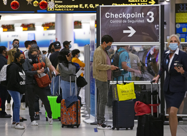 미국에서 코로나19 확산세가 계속되는 가운데 28일(현지시간) 플로리다주 마이애미 국제공항에서 마스크를 착용한 여행객들이 검색대를 통과하기 위해 줄지어 서 있다. ‘집에 머물라’는 보건 당국의 경고에도 불구하고 크리스마스를 전후해 여행객이 급증하면서 코로나19 확산을 부채질할 것이란 우려가 일고 있다./AP연합뉴스